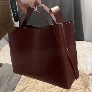 Vinröd väska från Gina - Snygg vinröd axelväska i stilren design med både korta handtag och lång axelrem. Väskan är sparsamt använd och är rymlig och snygg inför hösten!😍🥰 Bara att fråga vid funderingar!