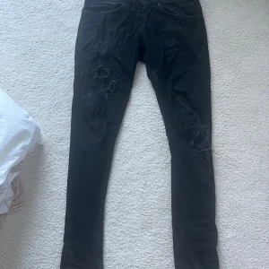 Dondup jeans - Svarta skinny jeans från Dondup  med slitna detaljer och hål på benen. Jeansen har klassisk femficksdesign och diskret D-logga på bakfickan. Snyggt smal passform och stretchigt jeanstyg som sitter tajt längs benen.