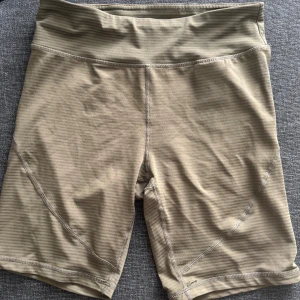 Olivgröna cykelbyxor  - Snygga olivgröna cykelbyxor med hög midja och tight passform. Perfekta för träning eller chill dagar. Tillverkade i ett stretchigt syntetmaterial som sitter skönt och följer kroppen. Snygga sömdetaljer som ger en sportig look.