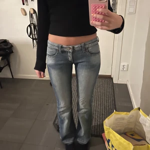 Lågmidjade bootcut jeans i ljusblå denim - Säljer ett par riktigt snygga lågmidjade jeans i ljusblå denim med bootcut-ben. Jeansen har klassiska fem fickor, dragkedja och knapp framtill.  Midjemåttet är 37 cm och Innerbenslängd är 74 cm