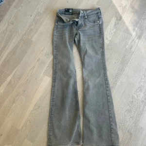 Snygga grå flare jeans låg midja Divided - helt nya! - Gråa flare jeans från Divided med låg midja och klassisk femficksdesign. Jeansen har en snygg tvättad look och utsvängda ben som ger en retrovibe. Perfekta för dig som gillar en avslappnad men trendig stil.