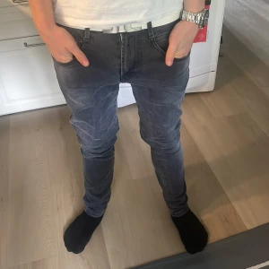 Grå slim fit jeans med snygga detaljer - Säljer ett par grå jeans med tvättad look och coola sömdetaljer på bakfickorna. Modellen är slim fit med smal passform och normal midja. Perfekta för dig som gillar en modern och stilren stil. St W29 L30