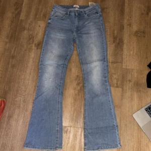 Blå bootcut jeans från ONLY - Snygga ljusblå bootcut jeans från ONLY med klassisk femficksdesign och normal passform. Jeansen har en lätt tvättad look och är tillverkade i mjukt bomullsmaterial med lite stretch. Tyget mellan låren börjar bli lite tunt, men inga hål. 