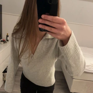 Ljusgrå stickad tröja med krage - Säljer en ljusgrå stickad tröja med v-ringning och bred krage. Tröjan har långa ärmar med ribbade muddar. Säljer då jag inte får användning av den längre. Tröjan är i storlek XS men passar även S. 