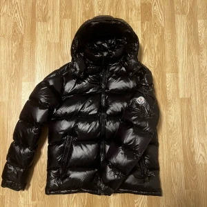 Moncler Maya  - Säljer en svart dunjacka från Moncler. Det är en  går ej att få bättre kvalitet. Maya i väldigt bra skick den är i nyskick i storlek L/4. Riktigt varm under vinter och riktigt skön. Bara skriva om ni vill ha någon bild eller undrar något