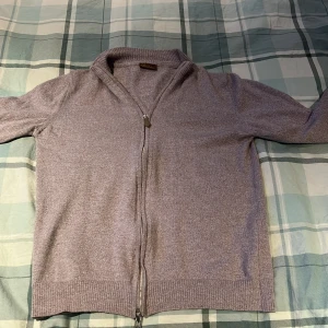 Beige/grå kofta från Stenströms med dragkedja - Säljer en stilren beige/grå kofta från Stenströms med hel dragkedja framtill. Storlek M men väldigt små i storleken så skulle säga Xs/small. Koftan är långärmad och har ribbade muddar vid ärmslut och nederkant. Perfekt för lager-på-lager och enkel att matcha med andra plagg.