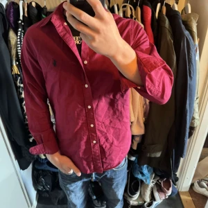 Ralph lauren skjorta - En stilig Vinröd Ralph Lauren Skjorta i fint skick! Använd fåtal gånger den är stor på mig men sitter bättre på mina kompisar. 72 cm är skjortans längd, tveka inte att skriva! 