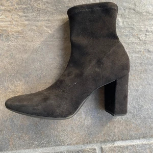 Svarta mocka stövletter med klack - Säljer ett par svarta stövletter i mjuk mocka med hög, bred klack och spetsig tå. Skorna har en stilren och minimalistisk design som passar till jeans eller kjol. De är enkla att dra på och ger en snygg siluett till outfiten. Passar perfekt att ha med ett par snygga jeans på en utekväll med tjejerna! Skorna är i storlek 40, men passar mig som har storlek 39. De har lite slitage eftersom dem är välanvända(se sista bilden), annars är det riktigt fina skor som passar till det mesta!