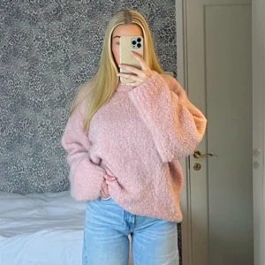 Ljusrosa fluffig stickad tröja - Supermysig ljusrosa stickad tröja med oversized passform och långa ärmar. Tröjan har en fluffig textur som gör den extra gosig och perfekt för kyliga dagar. Enkel rund halsringning och avslappnad stil som är lätt att matcha med jeans eller kjol.