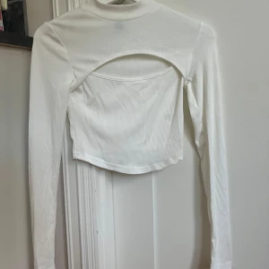 Vit croppad långärmad topp Shein - Säljer en vit croppad långärmad topp från Shein. Toppen har en cool cut-out detalj framtill och är tillverkad i ribbad polyester. Aldrig använd 