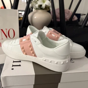 Valentino sneakers  - Ikoniska Valentino sneakers, strl 38 – för dig som vill sticka ut utan att kompromissa med komforten. De vita och rosa färgerna gör dem till ett riktigt statement-piece! Skorna är fräscha och redo för sin första äventyr. 💖