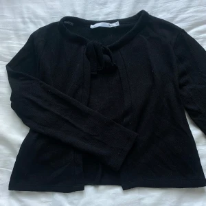 Svart kofta med knyt - Svart, stickad kofta från lager 157 i storlek XS. Nästan helt oanvänd, inga synliga defekter. Koftan har knytning framtill vid halsen