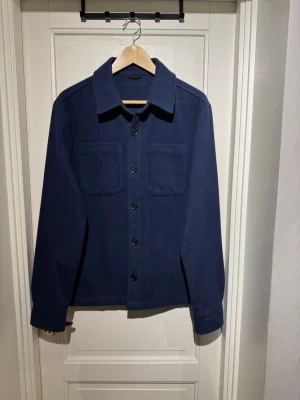 Mörkblå overshirt från D'once de la sense - Säljer just nu denna stilrena och eftertraktade Overshirten från D’once de la sense! Overshirten är slutsåld överallt och går inte att få tag på, så först till kvarn…. Storleken är S så Passar dig som är runt 175 - 185 ungefär. Skick 10/10.  Tveka inte att höra av er vid minsta lilla funderingar!🤩