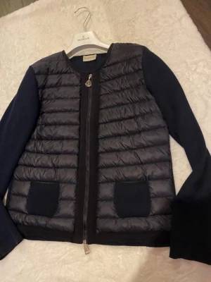  Moncler cardigan - Moncler marinblå cardigan, väldigt sparsamt använd och i mycket gott skick. Storlek M, men passar även mindre storlekar bra👌 självklart äkta, intyg av Monclers hemsida finns att tillgå samt qr-kod i jackan. Fin kvalitet och dyr i inköp