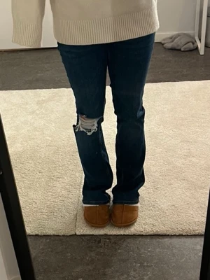 Lowwaist bootcut jeans från Zara - Snygga low waist jeans från zara med bootcut-passform och en mörkblå tvätt. Uppsydda i längden men inget som syns och passar perfekt på mig som är 165 cm. Jeansen har en snygg slitning på ena knät  Använda fåtal gånger. Skriv gärna om frågor finns🩵