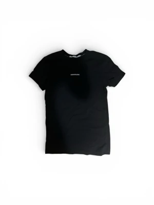 Svart t-shirt Calvin Klein Jeans - Svart t-shirt från Calvin Klein Jeans med vit logotyp tryckt på bröstet. Klassisk rund hals och korta ärmar. Tillverkad i mjuk bomull som känns skön mot huden. Perfekt för dig som gillar stilrena och enkla plagg med en touch av designer.