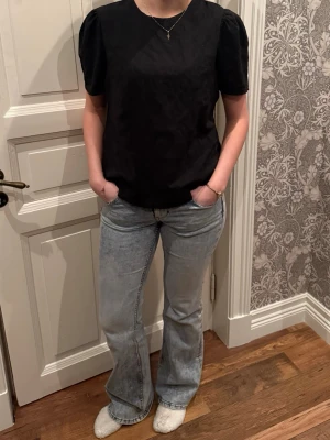 Svart blus med puffärm - Säljer en svart blus med korta puffärmar och rund hals. Toppen har en enkel och stilren design utan mönster eller detaljer, och är tillverkad i ett mjukt tyg som ger en skön känsla. Perfekt att matcha med jeans eller kjol för en clean look.