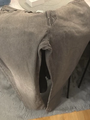 Grå jeans från Jack & Jones - Säljer ett par grå jeans från Jack & Jones med klassisk femficksdesign och ljus tvätt. Jeansen har raka ben och normal passform, med detaljer som bälteshällor och knappstängning. Perfekt för dig som gillar en enkel och stilren look.