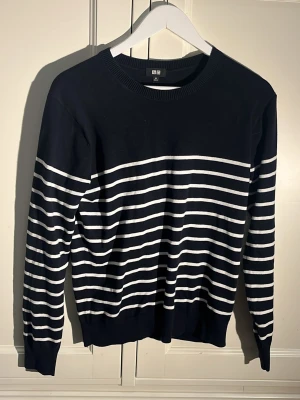 Randig stickad tröja - En snygg stickad randig tröja i vit och mörkblå/svart. Den är i XS herr från uniqlo. Passar från 160-170 skulle jag säga kan bero på lite. Fint skick!