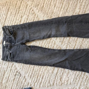 Grå jeans från Gina Tricot, storlek 140 - Säljer ett par grå jeans från Gina Tricot i storlek 140. Modellen har raka ben, klassisk femficksdesign och dubbla knappar fram. Jeansen är tillverkade i bomullsmaterial och har en mörkgrå ton som passar till det mesta.