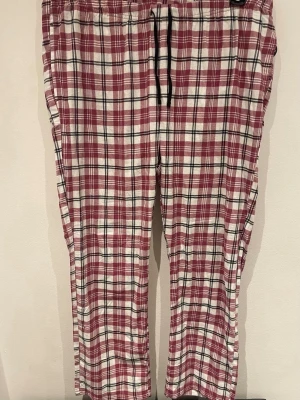 Rödvita rutiga mjukisbyxor XL - Rutiga mjukisbyxor i rött och vitt från Relax Good Night, storlek XL. Byxorna har svart snörning i midjan och är gjorda i mjuk bomull. Perfekta för chill dagar hemma eller när du vill vara extra bekväm. Klassisk loose passform och elastisk midja.