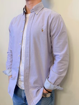 Ljuslila Ralph Lauren skjorta - En stilren skjorta från Ralph Lauren Second hand men i väldigt fint skick ✨ Tvättad och struken – redo att användas direkt.  Perfekt för en lite festligare look med väldigt snygga mönster i ärmslut samt krage.  Inga defekter och slim fit.  Storlek 👔: M Nypris 💰: ca 1 300 kr 