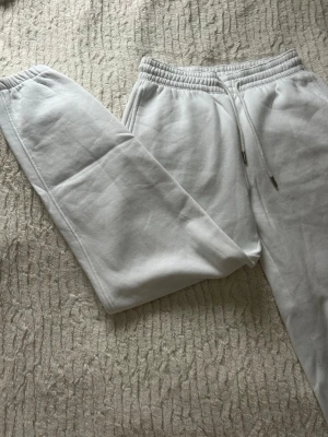 Vita mjukisbyxor med snörning - Säljer ett par vita mjukisbyxor med elastisk midja och snörning. Byxorna har ribbade muddar vid bensluten och är tillverkade i mjukt bomullsmaterial. Perfekta för chill dagar hemma eller när du vill vara extra bekväm.