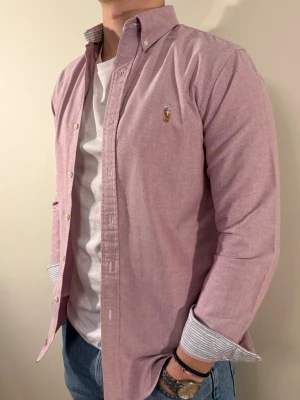 Ljuslila Ralph Lauren skjorta - En snygg polo skjorta när du vill klä dig något finare! Väldigt bra allround för fest eller middagar.  Snyggt mönster i ärmsluten om man viker upp ärmarna och även i kragen. Storlek👔: S Nypris💰: ca 1399 kr