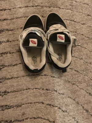 Svarta Vans sneakers med vit sula - Säljer ett par klassiska Vans sneakers i svart med vit sula och vita snören. Skorna har rund tå och är tillverkade i canvas och syntetmaterial. Ikonisk Vans-logga på plösen och sidan. Perfekt för dig som gillar streetstyle och skate.
