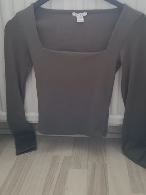 Brun långärmad topp från Amisu - Säljer en stilren brun långärmad topp från Amisu i storlek XS. Toppen har en fyrkantig halsringning och är figurnära i modellen. Perfekt att matcha med jeans eller kjol för en snygg look.
