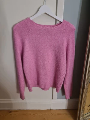 Rosa stickad tröja från Vero Moda - Mysig rosa stickad tröja från Vero Moda i storlek XS. Tröjan har en rund halsringning, ribbade muddar vid ärmslut och nederkant samt långärmad passform. Perfekt för dig som gillar färgglada och bekväma plagg.