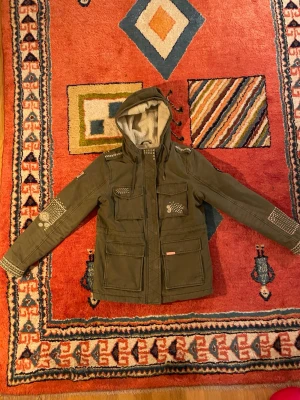 Fodrad Superdry jacka  - Fodrad Superdry jacka i storlek M, närmre S. Detaljer i Rosa och vit med en härlig grön ton. Mått: Armhåla t Armhåla ca 51cm………….längd från axeln ca 64cm………………armlängd från armhåla ca48cm…………