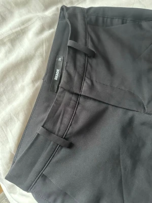 Svarta bootcut kostymbyxor Bik Bok - Snygga svarta kostymbyxor från Bik Bok i storlek 34. De är flare bootcut. Skrynkliga men man får stryka. Ser ut som nya. Innerbenslängd 80cm midjemått 34 rakt över. 