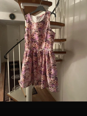 Floral Pink & Purple Sleeveless Dress – Size M – Fit & Flare - Beautiful sleeveless dress with a pink and purple floral pattern. Features a flattering fit & flare silhouette with a fitted waist and softly pleated skirt. Fully lined for comfort and structure. Zipper closure at the back. Perfect for summer events, parties, weddings, birthdays or casual chic occasions. In very good condition – no visible flaws. Brand: 2X THE BIZ Size: M Color: Pink / Purple / Floral Length: Above the knee Style: Fit and flare, feminine, elegant Material: Lined fabric (see phot