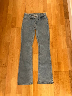 Levi's 715 Bootcut jeans ljusblå - Ljusblå Levi's 715 Bootcut jeans med klassisk femficksdesign och ikonisk röd Levi's-tag på bakfickan. Jeansen är i storlek 24