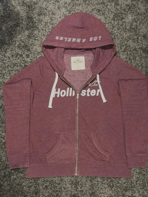 Hollister zipper hoodie - Säljer denna röda zipper hoodie från märket Hollister. Väldigt bra skick och storleken är L men passar bättre som M. Skicka ett meddelande om du har frågor eller vill ha mer bilder! :)