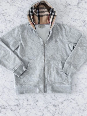 Burburry zip grå - Säljer nu denna feta burberry zip 🙌Den är i bra skick förutom att snöret vid luvan har lossnat. Allt vi säljer är 100% äkta.Tveka inte på att höra av dig vid frågor 🤝