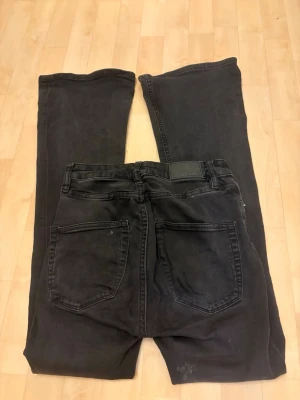 Svarta boot cut jeans 157, S - Säljer ett par svarta boot cut jeans från 157 i storlek S. Byxorna har utsvängda ben och klassisk femficksdesign. Materialet är mjukt och stretchigt, vilket gör dem riktigt sköna att bära. Jeansen har två fläckar där bak, ena på fickan och andra vid låret därför säljer jag de billigt