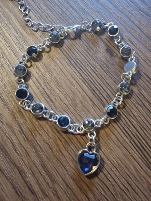 Armband heart of ocean - Ett fint armband med silverfärgade detaljer och mörkblå/gråa stenar.Armbandet har ett hänge i form av ett hjärta.