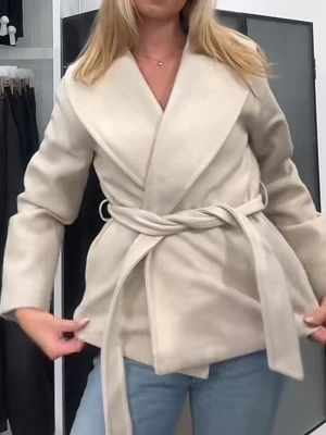Beige kappa från Vero Moda - Snygg beige jacka från Vero Moda med bred krage och omlottmodell. Jackan har ett matchande bälte i midjan och raka, långa ärmar. Perfekt för lager-på-lager och enkel att styla till jeans eller kjol. Materialet är mjukt och ger en lyxig känsla. Har inte använt den säljer för att den inte var min stil. ordinarie priset är 749kr och den är slut i den här färgen 💕✨✌️