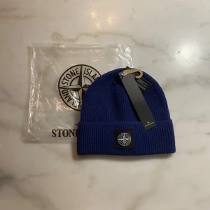 Sttone issland Mössa - Stilren ribbstickad mössa i mycket bra skick. Klassisk design med diskret patch framtill. Oanvänd, originaltags och förpackning medföljer. Perfekt till vardag och streetwear. One size – passar de flesta. Skickas snabbt.