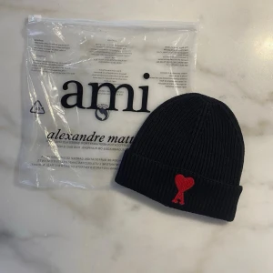 Svart ribbstickad mössa från Amiii - Stilren mössa med broderad hjärtlogga framtill. Klassisk ribbstickad modell som passar både till vardag och mer uppklädda outfits. Bekväm passform och tidlös design. Sparsamt använd och i mycket fint skick. 