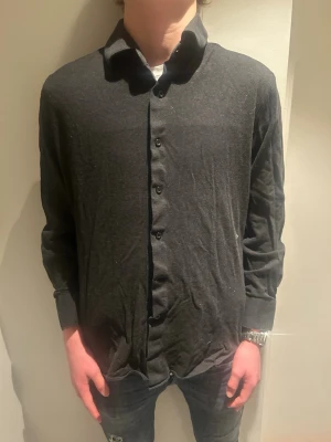 Svart långärmad skjorta med knappar - En stilren svart skjorta med lång ärm och klassisk krage. Skjortan har knäppning framtill och är gjord i ett mjukt material som känns skönt mot huden. Passformen är normal och den är enkel att matcha med olika outfits.modellen är 184, tveka inte på att höra av er vid frågor! Pris kan diskuteras vid snabb affär😀