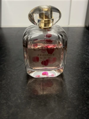 Escada Celebrate N.O.W. parfym - 80% av en Snygg parfym från Escada med lekfull design och hjärtan i flaskan. Perfekt för dig som vill ha en unik accessoar på sminkbordet. Namnet 'Celebrate N.O.W.' syns tydligt på flaskan.