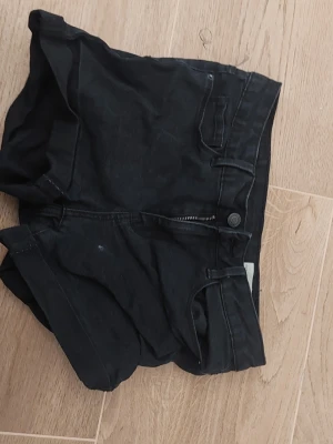 Svarta shorts från Vero Moda - Säljer ett par svarta shorts från Vero Moda i klassisk jeansmodell. De har hög midja, dragkedja och knapp framtill samt fickor både fram och bak. Perfekta till sommaren och lätta att matcha med olika stilar.