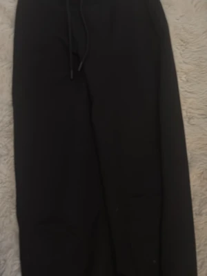 Svarta mjukisbyxor från 157 XS - Svarta mjukisbyxor från 157 i storlek XS. Byxorna har dragsko i midjan för skön passform och är gjorda i mjukt material som passar perfekt för chill dagar. Klassisk enkel design utan synliga loggor eller detaljer.