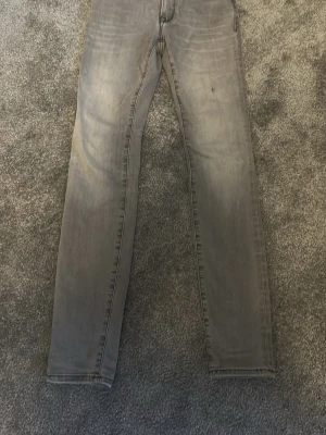 Replay grå skinny jeans  24/30 - Säljer ett par grå skinny jeans från Replay i storlek 24/30. Jeansen har klassisk femficksdesign, svarta detaljer och Replay-logga på bakfickan. Snygg tvättad look och smal passform som sitter tajt längs benen. Perfekta till sneakers eller boots. Pris går att diskutera vid snabbb affär 