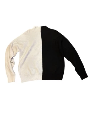 Svartvit stickad tröja - Säljer en unik stickad tröja med coolt svartvitt blockmönster. Ena halvan är helt svart och andra halvan är vit, vilket ger en riktigt snygg kontrast. Tröjan har rund hals och långa ärmar, perfekt för dig som vill sticka ut lite extra.