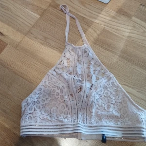 Spets halterneck från NLY  - Supersöt ljusrosa linnetopp från NLY Lingerie i spets med blommigt mönster. Toppen har hög hals med justerbara bandl och hakknäppning i ryggen. Perfekt för sommarvärmen  eller som statement piece.