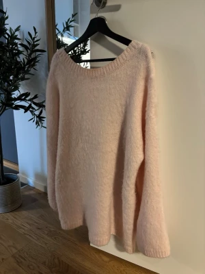 Oversized stickad tröja från Gina Tricot - Oversized mysig ljusrosa stickad tröja med öppen rygg. Tröjan är i mycket bra skick och har varit väl omhändertagen.